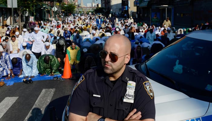A New York City police officer stands guard as Muslims pray during the Eid holiday that marks the end of the Muslim holy month of Ramadan in the Brooklyn borough. — Reuters
