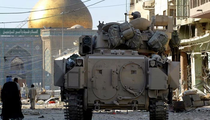 A US Army Bradley armoured vehicle of the 1st Cavalry division guards a street leading from the cemetery to Imam Alis shrine, in Najaf, Iraq, August 27, 2004. — Reuters