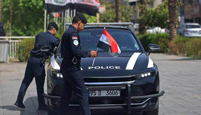 A policeman prepares to place an Iraqi flag on a police vehicle at the Tahrir Square in Baghdad on September 29, 2026.— AFP