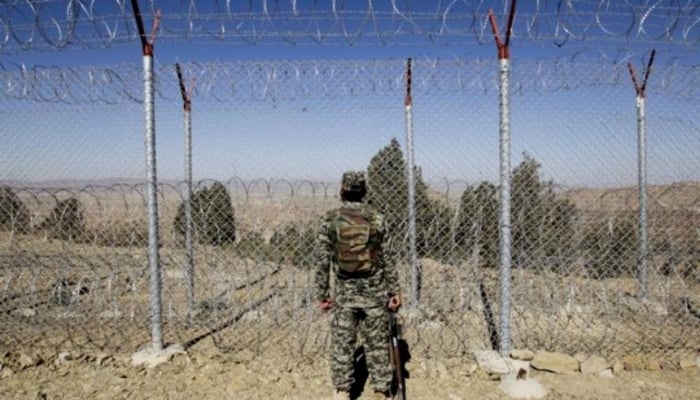 A Pakistani soldier stands guard along the fence at an outpost on the Pak-Afghan border. — Reuters/File