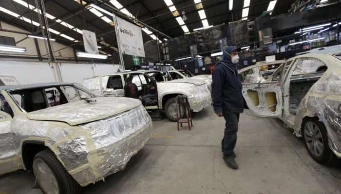 A technician walks near cars to be fitted with armor plating and bulletproof windows at a garage in Mexico City on December 15, 2010. — Reuters
