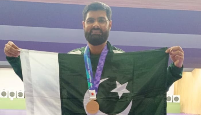 Pakistan shooter Ghulam Mustafa Bashir poses with his medal and Pakistan flag after success at Asian Games 2026 on October 1, 2026. — Reporter