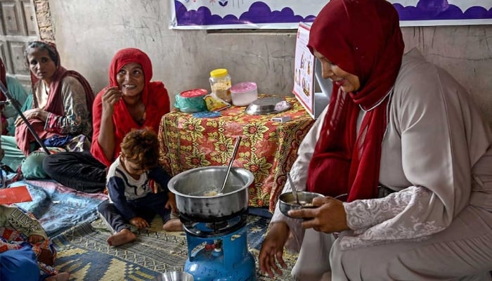 This photograph taken on July 29, 2025 shows a female health worker (right) teaching mothers how to prepare nutritious meals for their children during a Unicef nutrition programme at Fateh Muhammad Soomro village in the Sujawal district of Sindh. — AFP