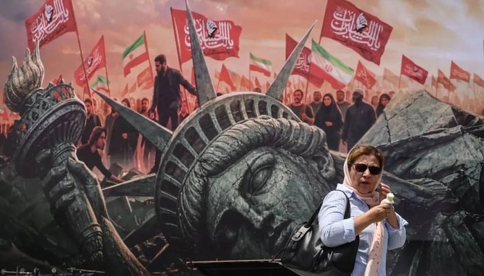 An Iranian woman walks past an anti-US billboard at Enghelab Square in central Tehran. — AFP/File