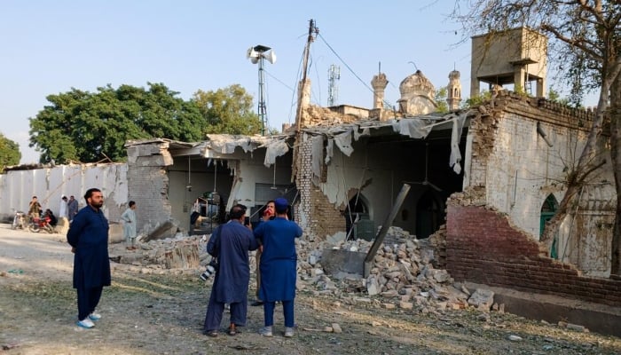 People stand near a damaged section of a police facility following a suicide attack in Kohat, KP, September 18, 2026. — Reuters