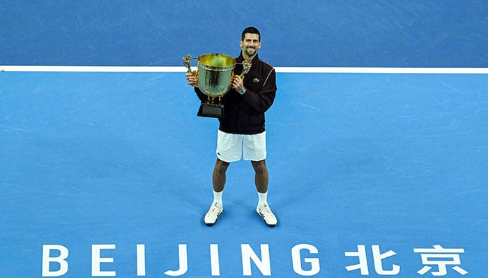 Serbias Novak Djokovic holds up the trophy as he celebrates winning the mens singles final against Australias Alex de Minaur at the China Open tennis tournament in Beijing on October 6, 2026. — AFP