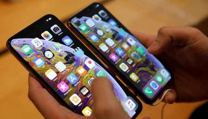 The image shows a person holding smartphones. — Reuters/File