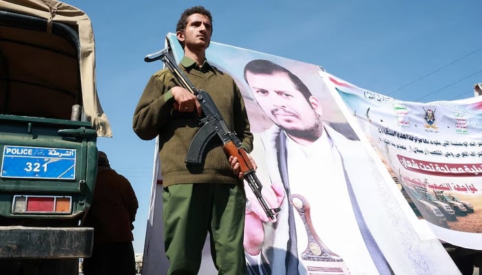 A member of Houthi security forces stands next to a poster of Houthi leader Abdul-Malik al-Houthi at the site of a gathering of Houthi supporters to show solidarity with the movement as fighting intensifies across several fronts, in Sanaa, Yemen, October 7, 2026.— Reuters
