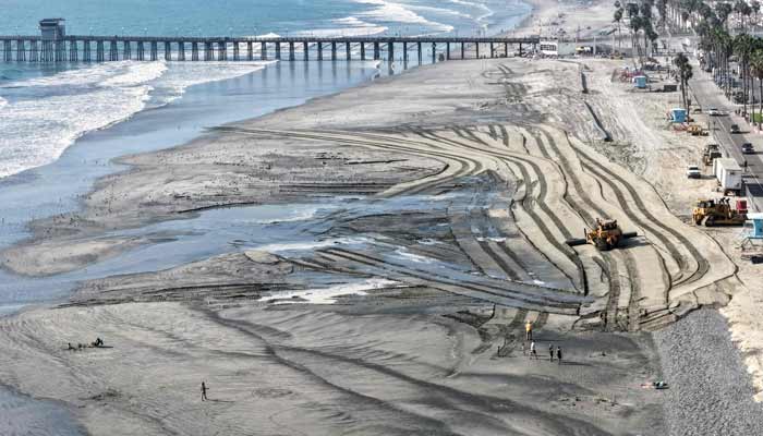 In an aerial view, work continues on a sand replenishment project along an eroded Pacific Ocean shoreline on October 7, 2026 in Oceanside, California. — AFP