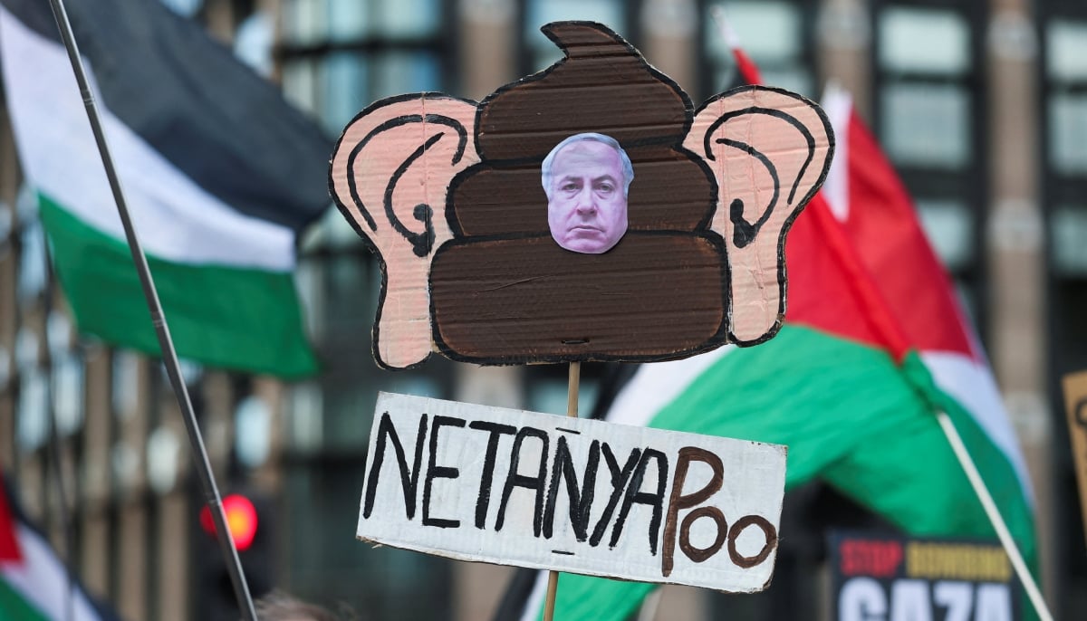 A demonstrator holds a sign featuring an image of Israeli Prime Minister Benjamin Netanyahu during a pro-Palestinian protest march through the city to mark the third anniversary of the war in Gaza, in London, Britain, October 10, 2026. — Reuters