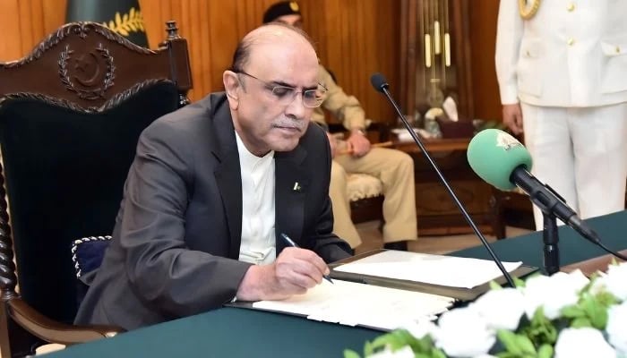 President Asif Ali Zardari signs a bill in this undated picture. — President House/File