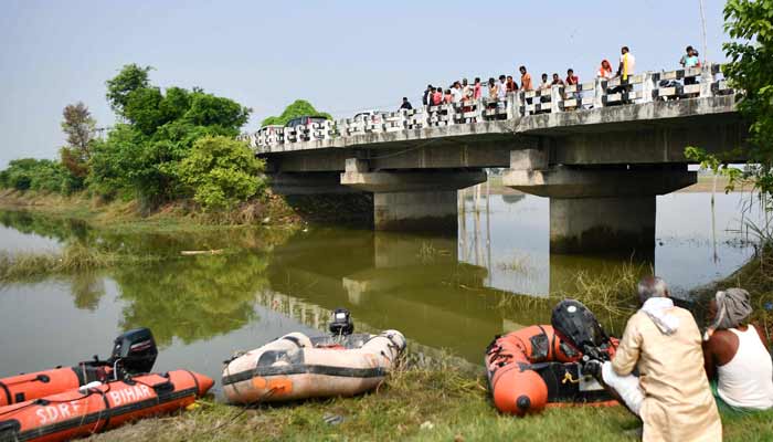 People watch from a bridge as rescue personnel conduct a search operation for the missing after a boat capsized in Ganga river in Bihars Vaishali district on October 14, 2026. — AFP