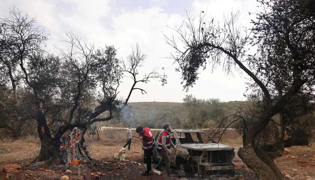 Palestinian volunteers douse an olive tree set alight along with a Palestinian-owned vehicle, reportedly by Israeli settlers, near the village of Turmus Ayya, north of the city of Ramallah, in the Israeli-occupied West Bank on October 16, 2026.— AFP