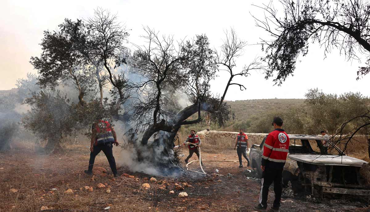 Palestinian volunteers douse an olive tree set alight along with a Palestinian-owned vehicle, reportedly by Israeli settlers, near the village of Turmus Ayya, north of the city of Ramallah, in the Israeli-occupied West Bank on October 16, 2026. — AFP