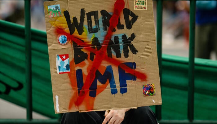 A protestor holds a placard with IMF and World Bank written on it with a red cross. — Reuters
