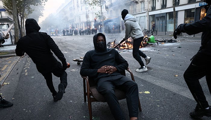 A masked protester sits on a chair as protesters block a street amid clashes during a day of demonstrations against the cost of living and rising fuel prices in Paris, France, October 17, 2026. — Reuters