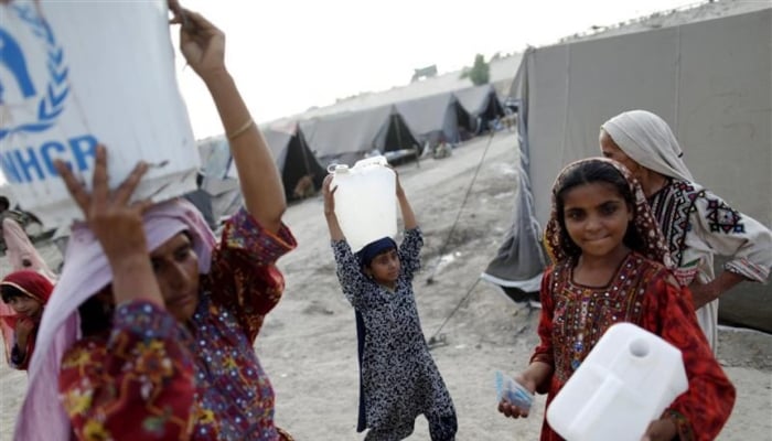 Flood victims carry plastic containers with clean water at a relief camp in Sukkur, Sindh. — Reuters/File