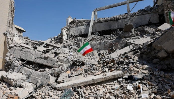 An Iranian flag stands in the rubble following a strike on a police station in Tehran, Iran, March 4, 2026. — Reuters