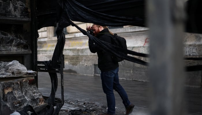 A person takes a photo of a newspaper stand burned during recent demonstrations in Paris ahead of nationwide protests called by the Yellow Vests movement joined by French high school and university students, against the cost of living and rising fuel prices in France, October 24, 2026. — Reuters
