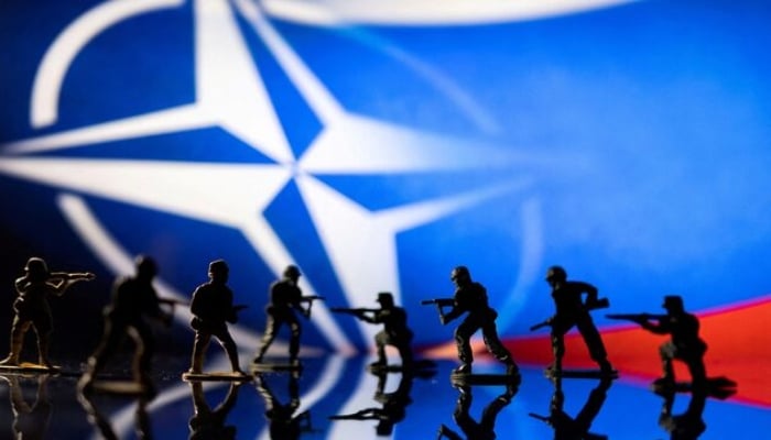 Army soldier figurines are displayed in front of the Nato logo and Russian flag colours background in this illustration taken, February 13, 2022. — Reuters