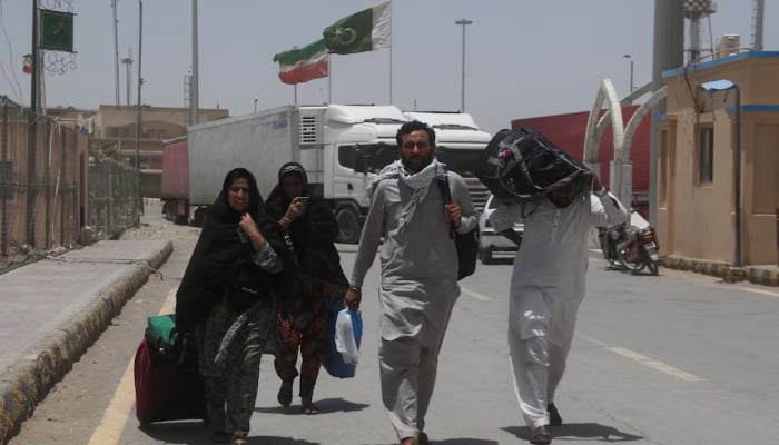 Pakistani pilgrims walk with their belongings after they returned from Iran, following the Israeli strikes in Iran, at the Pakistan-Iran border crossing in Taftan, Pakistan June 19, 2025. — Reuters