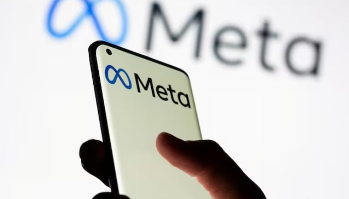 Woman holds smartphone with Meta logo in front of a displayed Facebooks new rebrand logo Meta in this illustration picture taken October 28, 2021. — Reuters