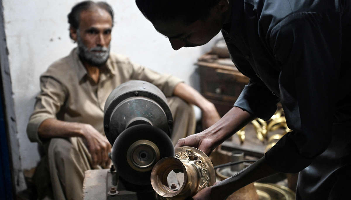 Antique dealer Shakeel Ahmed watches as his son polishes an artefact at their restoration workshop in Rawalpindi on October 20, 2026.— AFP