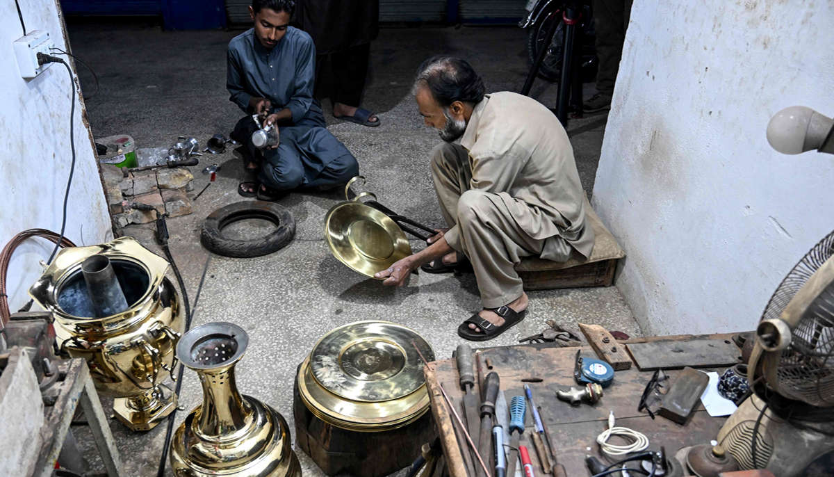 Antique dealer Shakeel Ahmed and his son restore artefacts at their workshop in Rawalpindi on October 20, 2026.— AFP