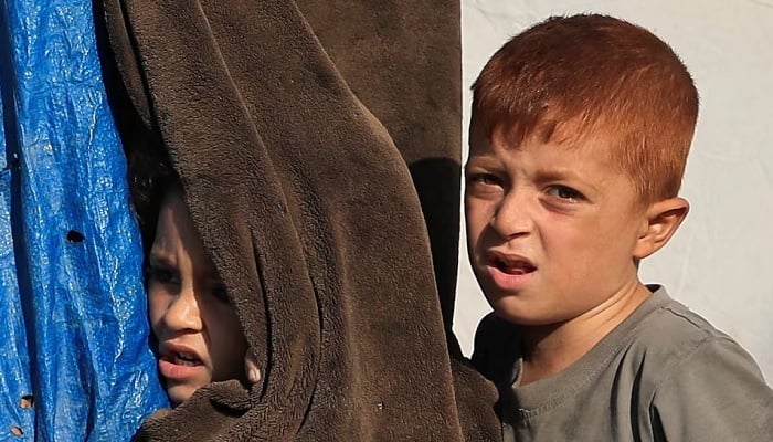 Children look on during the funeral of three Palestinians who were killed in an Israeli strike, according to medics, in Gaza City, October 25, 2026.— Reuters