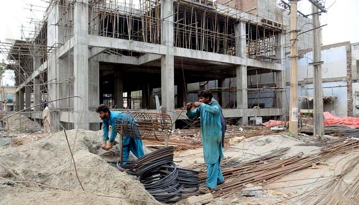 Labourers are busy with their work during the construction of the building on Canal Road in Faisalabad on May 20, 2023. — Online